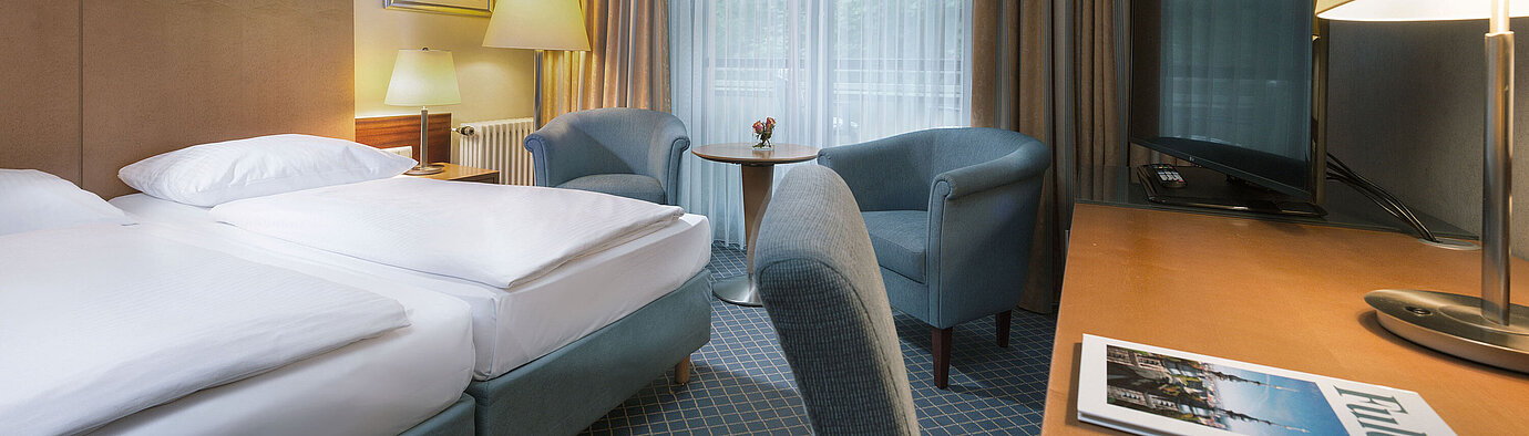Comfort room  Comfortable double room at Maritim Hotel Fulda with modern furnishings, desk, and cozy seating area.