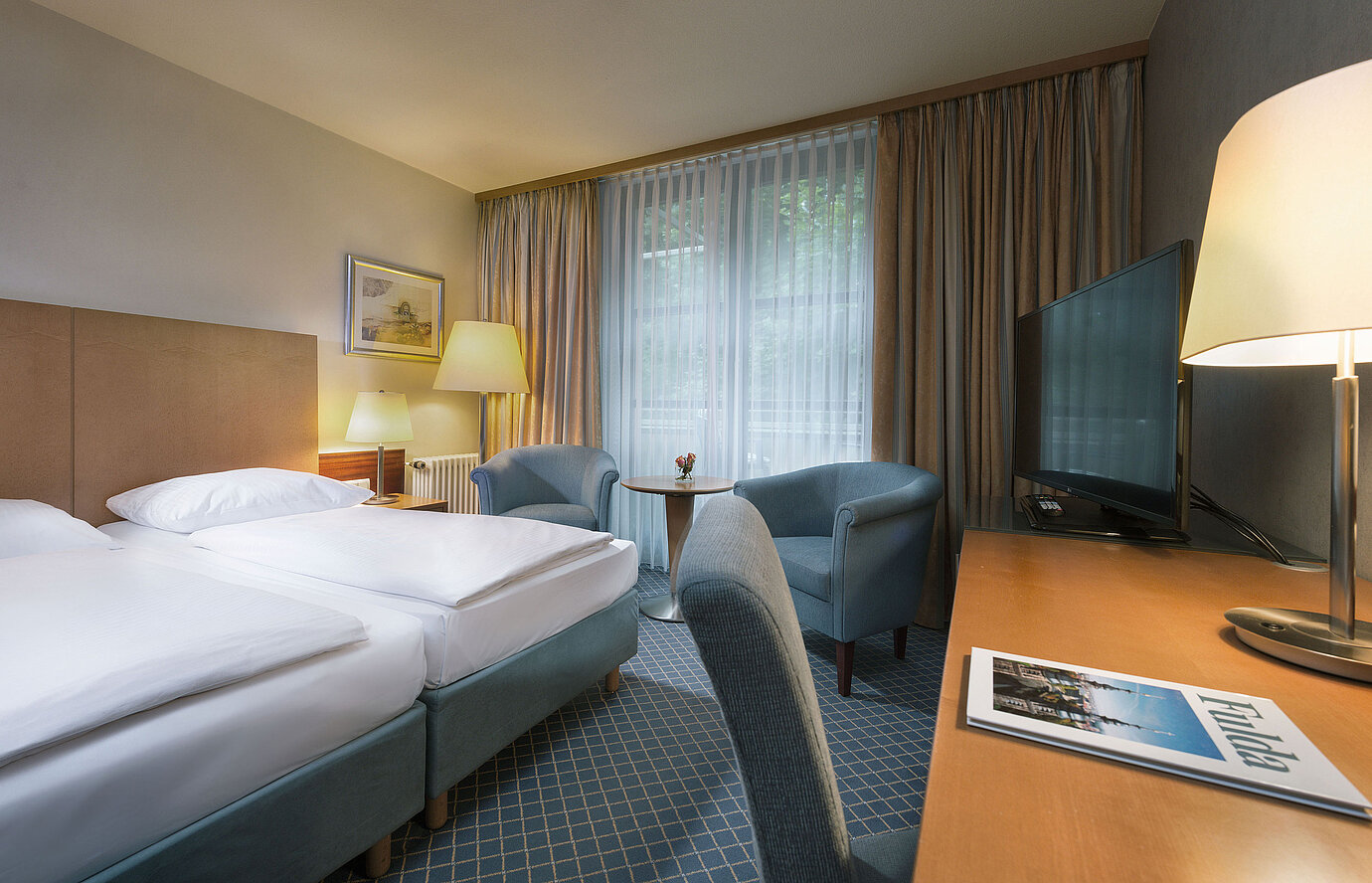 Comfortable double room at Maritim Hotel Fulda with modern furnishings, desk, and cozy seating area.