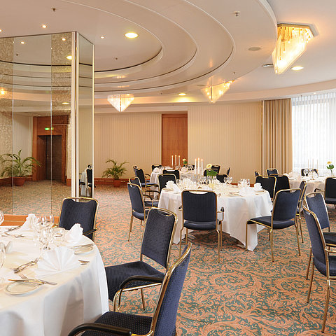 Salon Dresden at Maritim Hotel Magdeburg with elegantly set white-clothed tables, candelabras, and stylish lighting for festive events.