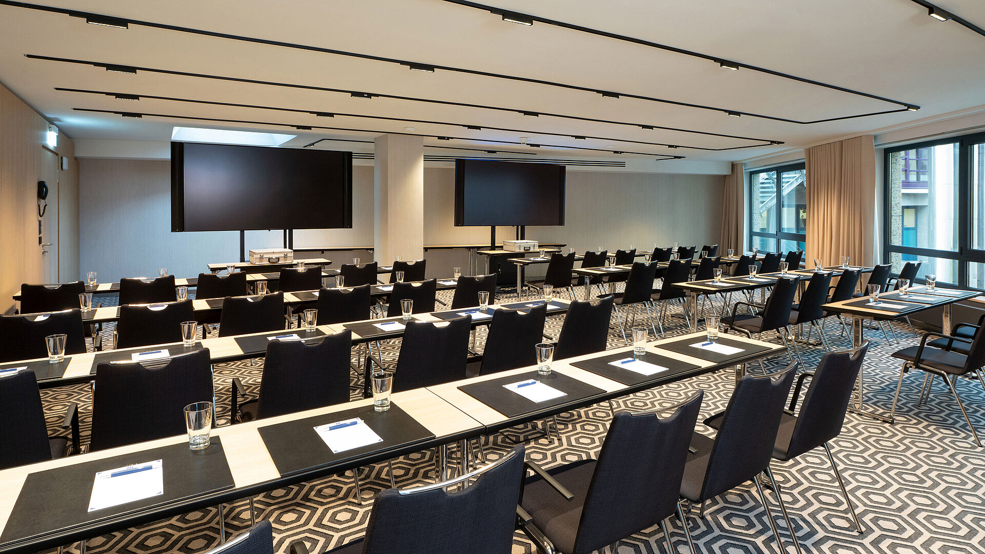 Meeting room 1 with classroom-style seating, conference tables, modern media technology and bright interior.