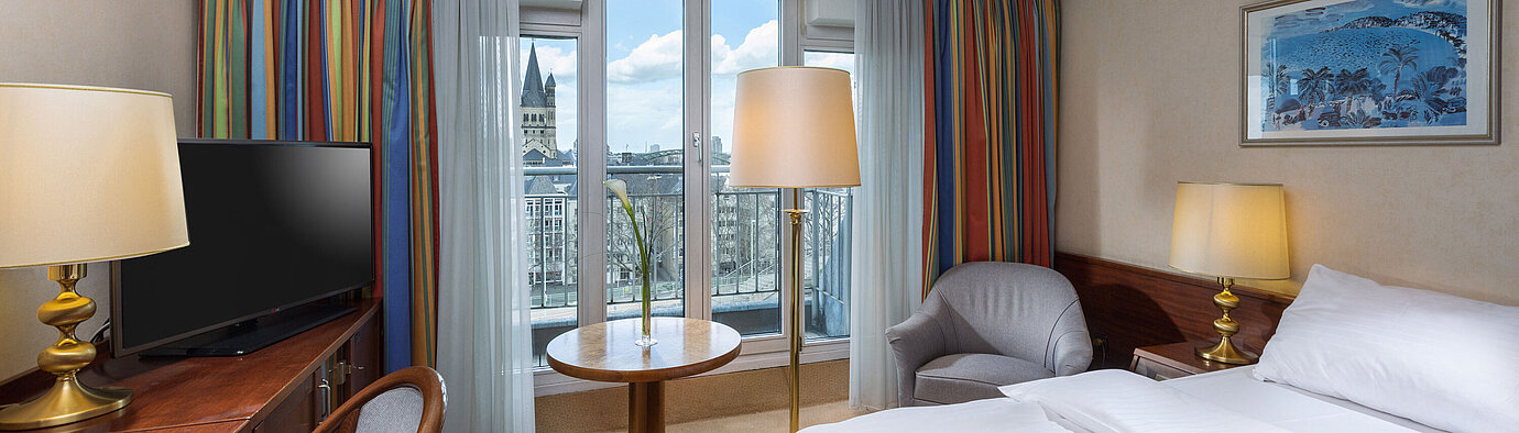 Classic room Classic room at Maritim Hotel Cologne with a double bed, desk, and view of the Rhine and historic city center.