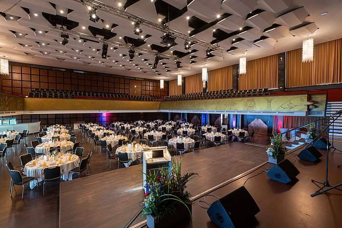 "Saal Maritim" with festively set tables, stage and seating for an event