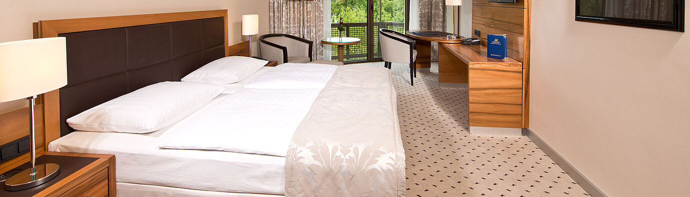Comfort room Bright room at Maritim Hotel Bad Homburg with cozy bed, desk, and balcony with green view.