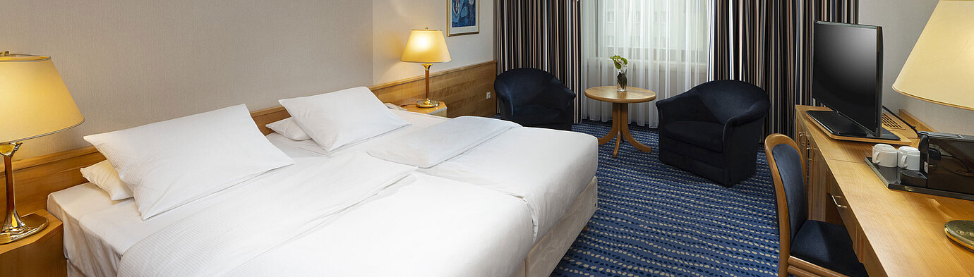 Superior room Large bed with bedside tables and lamps, next to seating area and desk.