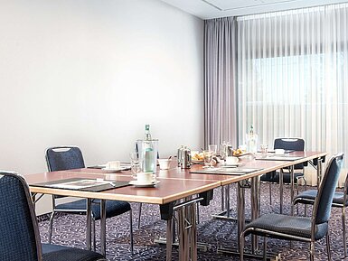 Modern conference room at Maritim Hotel Darmstadt with table setup, natural light, and a coffee break arrangement.