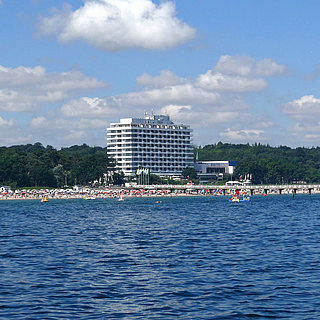 Maritim Seehotel Timmendorfer Strand, pier, and colorful flags from a boat on a sunny day.