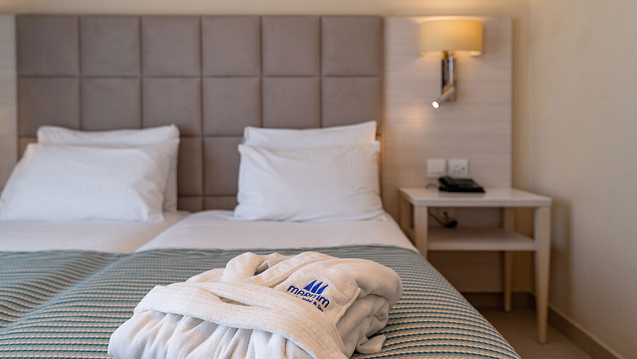 Deluxe room Close-up of a hotel bed with bathrobe and soft bedding