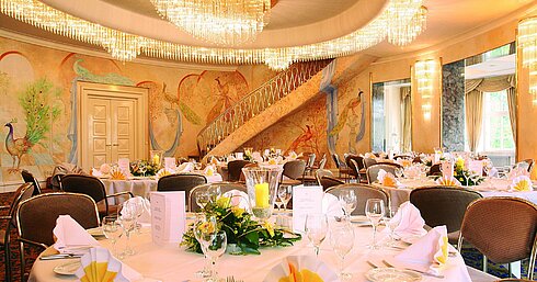 Elegant banquet hall with wall paintings, chandeliers and festively set tables