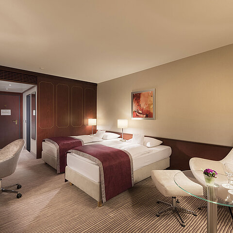 Comfort room at Maritim Hotel Bonn, featuring two single beds, armchair, desk, and modern lighting.