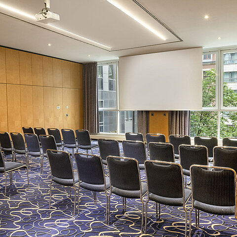 Modern conference room at Maritim proArte Hotel Berlin with rows of chairs and screen.
