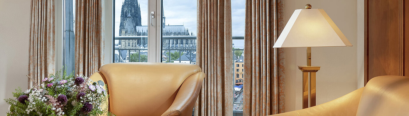 Deluxe Suite Elegant Heumarkt Suite at Maritim Hotel Cologne featuring comfortable leather chairs and a direct view of Cologne Cathedral.