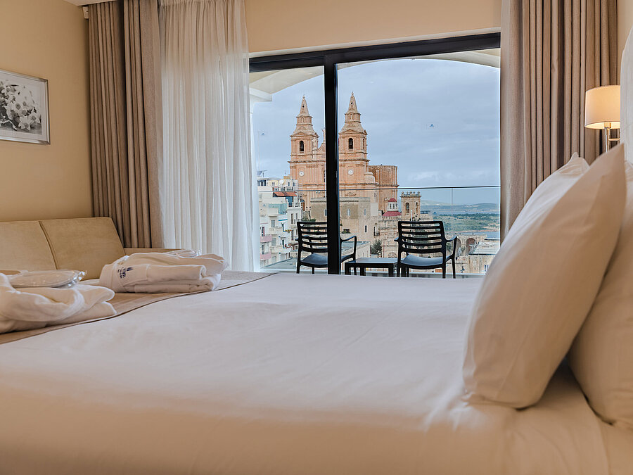 Deluxe Family Suite Hotel room with double bed, balcony and views of historic church and city