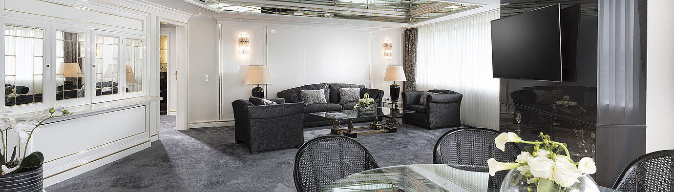 Stylish living room of the luxury suite at Maritim Hotel Bonn with mirrored ceiling, modern furniture, and large dining table.