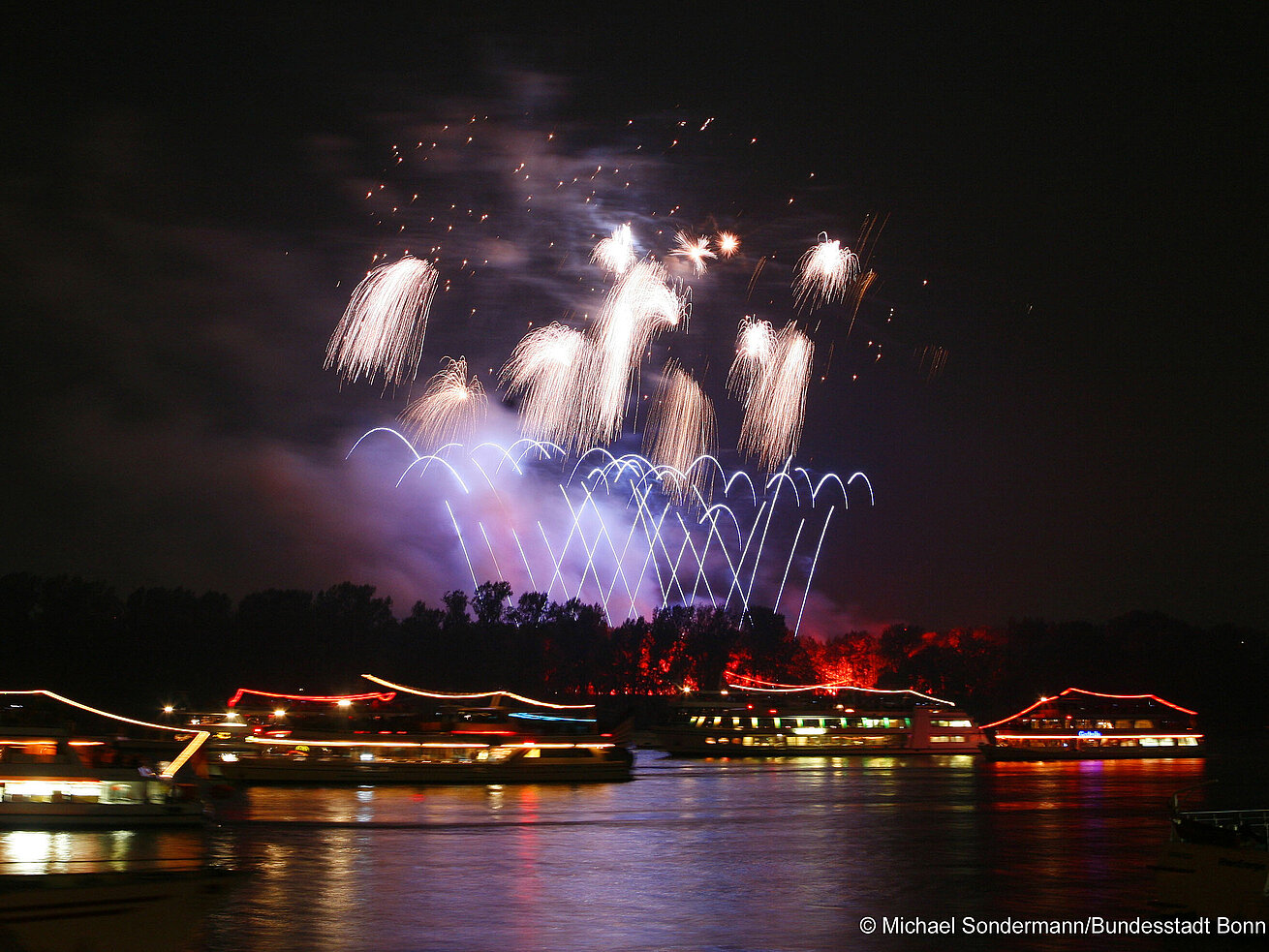 Rhine in flames Fireworks lighting up the night sky above a river with illuminated boats
