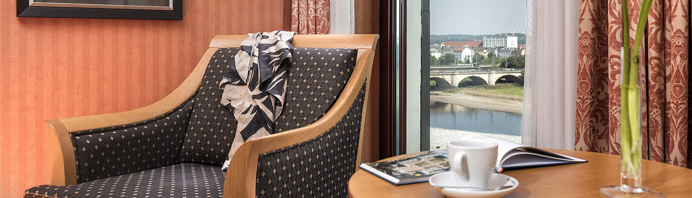 Detail of the hotel room Cozy armchair detail with a view of the Elbe River and bridge, decorated with a scarf on the backrestCozy armchair detail at Maritim Hotel Dresden with a view of the Elbe River and bridge, decorated with a scarf on the backrestCozy armchair detail at Maritim Hotel Dresden with a view of the Elbe River and bridge, decorated with a scarf on the backrestCozy armchair detail at Maritim Hotel Dresden with a view of the Elbe River and bridge, decorated with a scarf on the backrest.