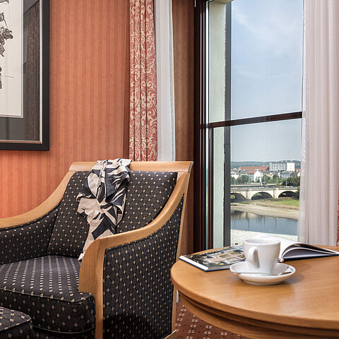 Cozy armchair detail with a view of the Elbe River and bridge, decorated with a scarf on the backrestCozy armchair detail at Maritim Hotel Dresden with a view of the Elbe River and bridge, decorated with a scarf on the backrestCozy armchair detail at Maritim Hotel Dresden with a view of the Elbe River and bridge, decorated with a scarf on the backrestCozy armchair detail at Maritim Hotel Dresden with a view of the Elbe River and bridge, decorated with a scarf on the backrest.