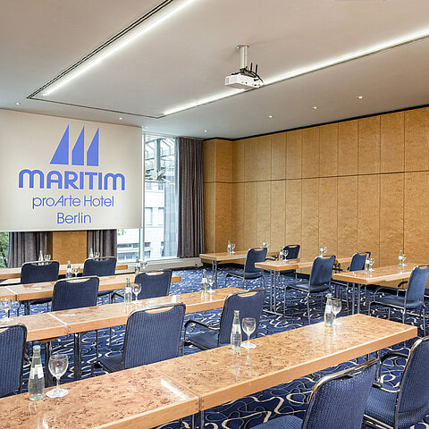 Conference room at Maritim proArte Hotel Berlin with row seating and projection screen.
