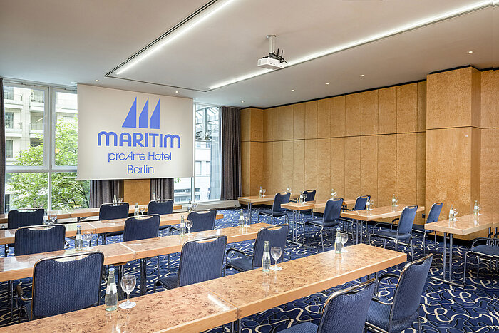 Conference room at Maritim proArte Hotel Berlin with row seating and projection screen.