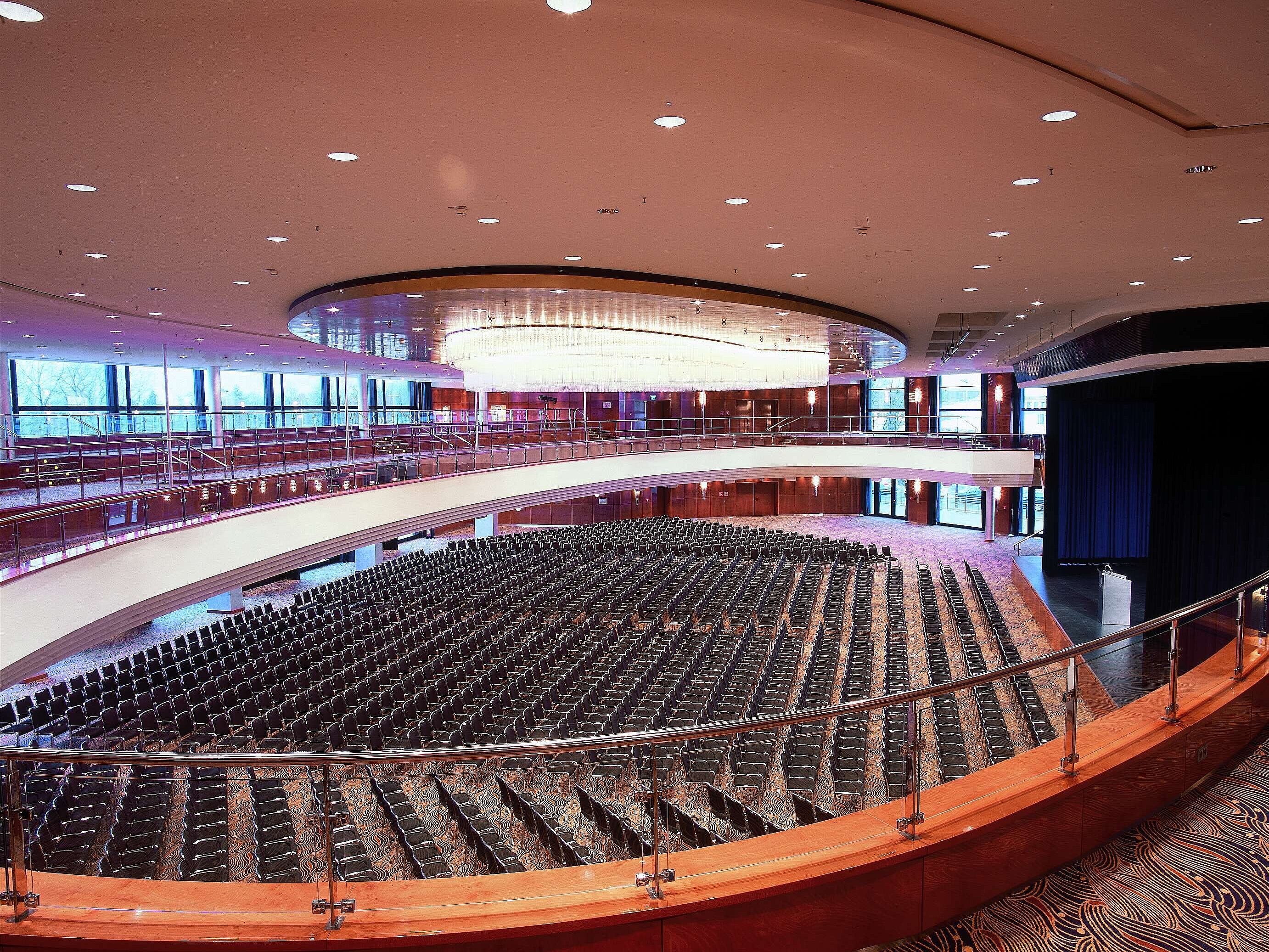  Elegant conference hall at Maritim Hotel Düsseldorf with hundreds of seats, modern architecture, and a large stage.