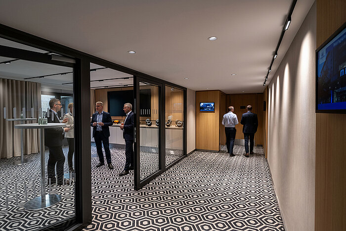 Coffee break area with standing tables, coffee station and guests talking during a conference break.