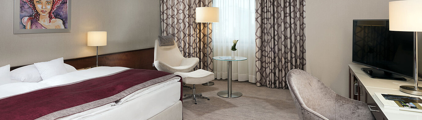 Comfort room at Maritim Hotel Bonn with cozy bed, chairs, desk, and modern curtains.