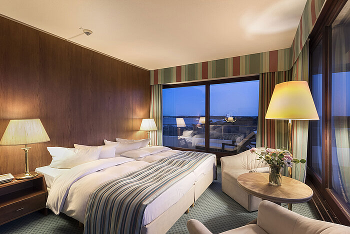 Superior room at Maritim Seehotel Timmendorfer Strand with double bed, seating area, floor lamps, and nighttime balcony view.