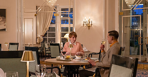 Guests dining in the Café-Restaurant Classic, enjoying a cosy evening in an elegant, warmly lit setting.