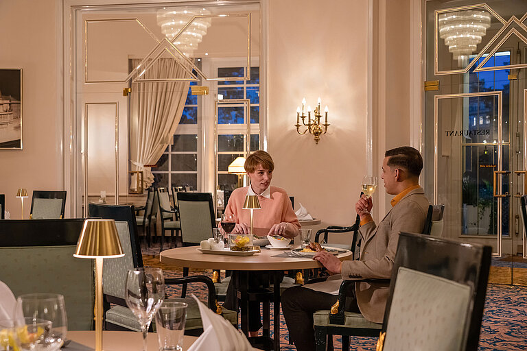 Guests dining in the Café-Restaurant Classic, enjoying a cosy evening in an elegant, warmly lit setting.