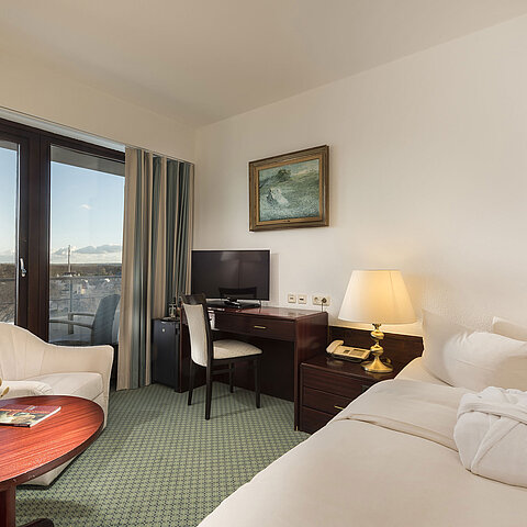 Bright single room at Maritim Seehotel Timmendorfer Strand with balcony, desk, cozy seating, and sea view.