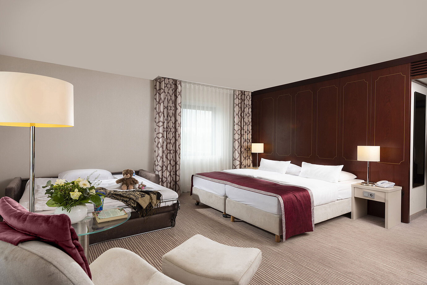 Comfort family room at Maritim Hotel Bonn with a large double bed, pull-out sofa, armchair, and flower arrangement.
