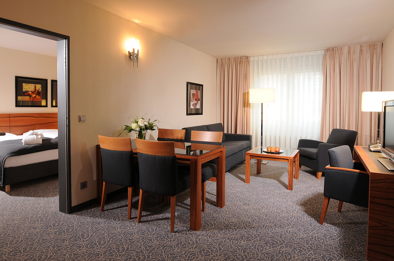 Spacious suite with living room, dining table and separate bedroom at Maritim Hotel Munich