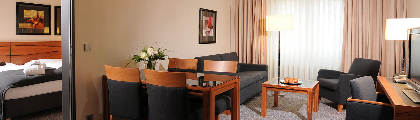 Spacious suite with living room, dining table and separate bedroom at Maritim Hotel Munich