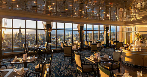 Restaurant in Maritim Hotel Ulm with elegant seating, panoramic windows and views over Ulm at sunset