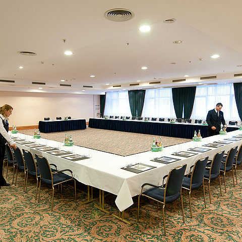 Conference room at Maritim Hotel Magdeburg with U-shaped seating, set tables, and staff preparations.