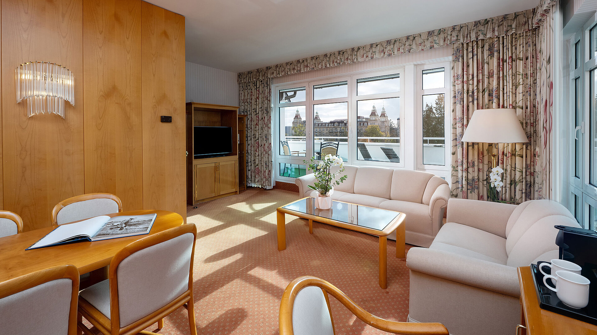 Junior Suite Junior Suite with bright living area, sofa, large window, dining space and classic interior at the Maritim Hotel.