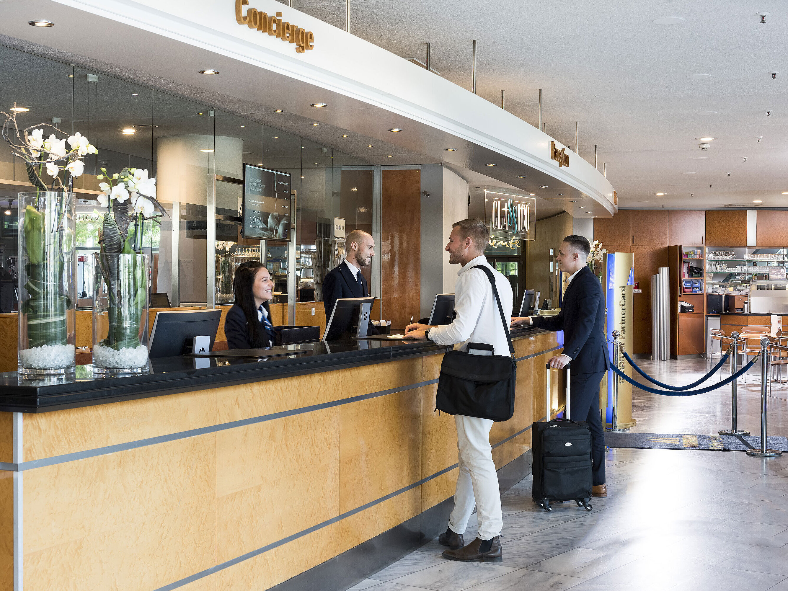 Friendly reception at the Maritim Hotel Frankfurt with guests and staff in a modern lobby.