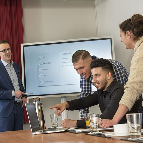 Team meeting in Salon Rhein at Maritim Cologne with a screen, laptops, and participants collaborating and presenting.