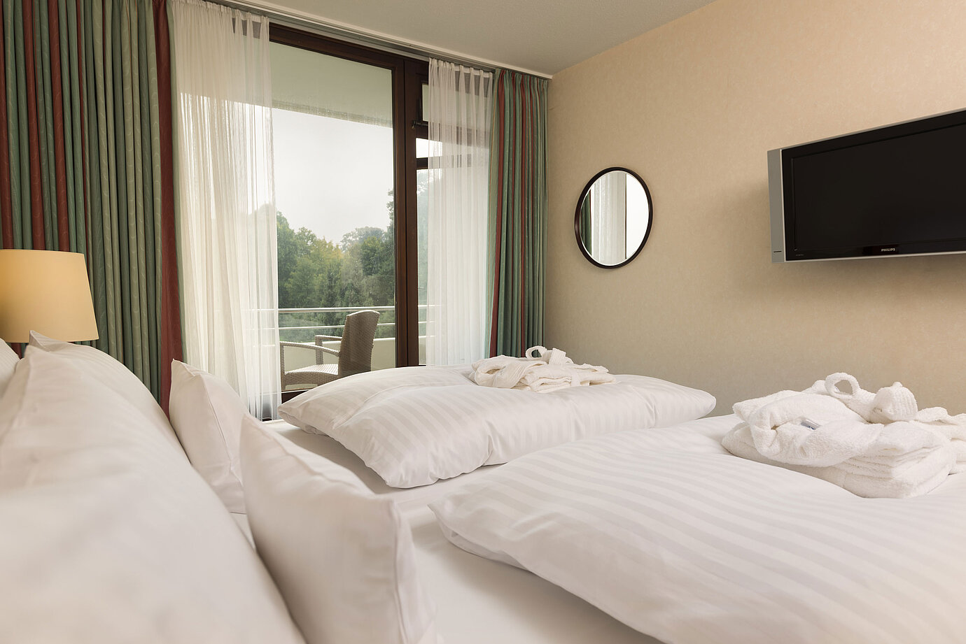 Double bed with TV, bathrobe and balcony view at Maritim Hotel Bad Salzuflen