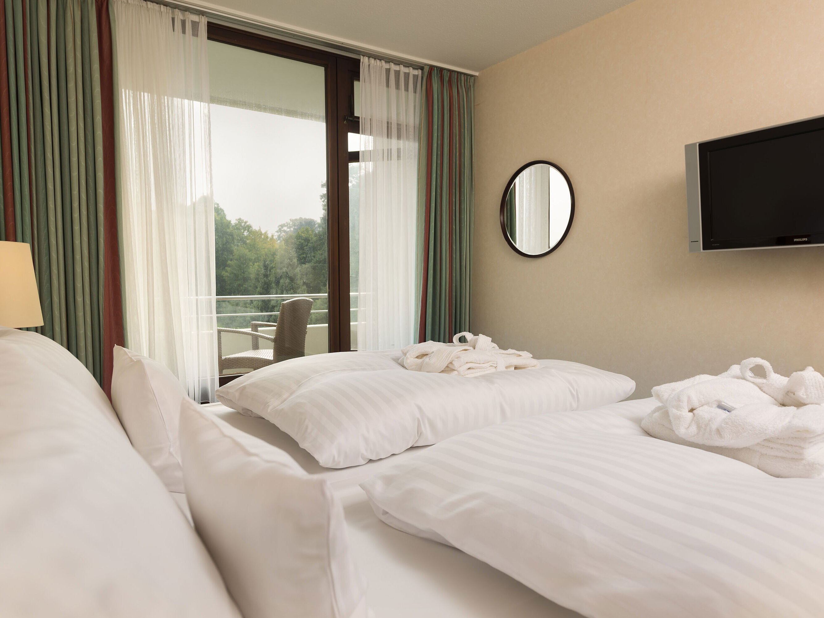 Double bed with TV, bathrobe and balcony view at Maritim Hotel Bad Salzuflen