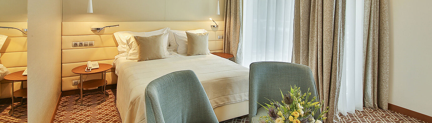 Modern hotel room with double bed, elegant furnishings, large windows and warm lighting