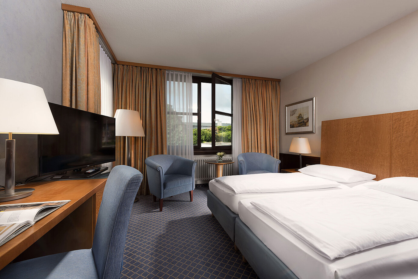 Classic room at Maritim Hotel Fulda with a cozy double bed, desk, seating area, and large window.