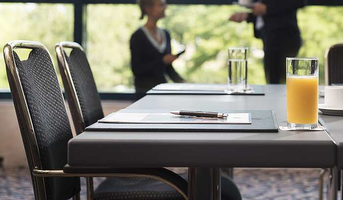 Modern meeting room with natural light, laptop, drinks, and informal conversation at Maritim Hotel Hannover.