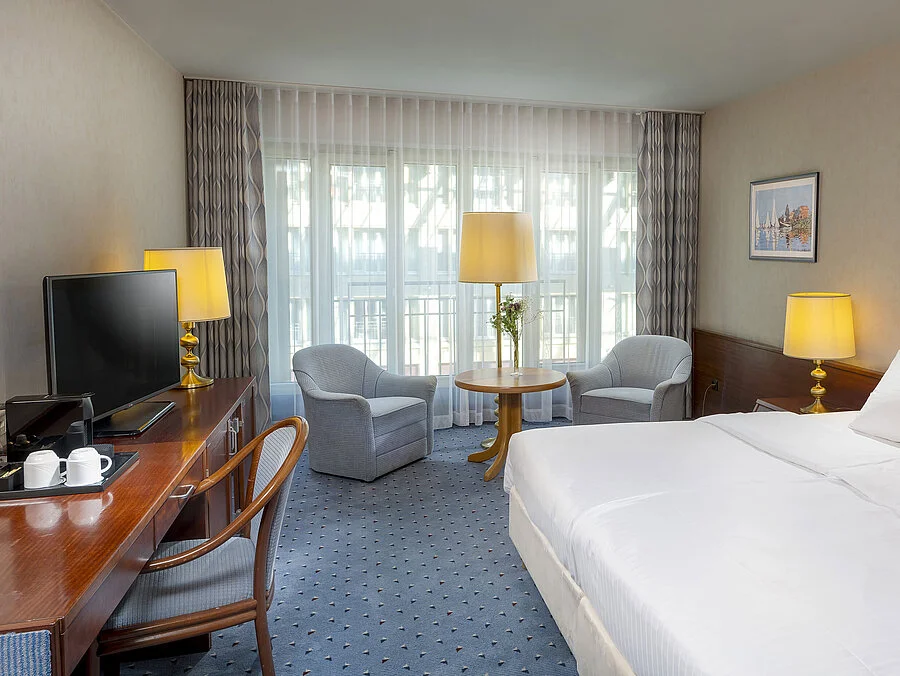 Classic room at the Maritim Hotel Cologne with a double bed, cozy seating area, desk, and TV.