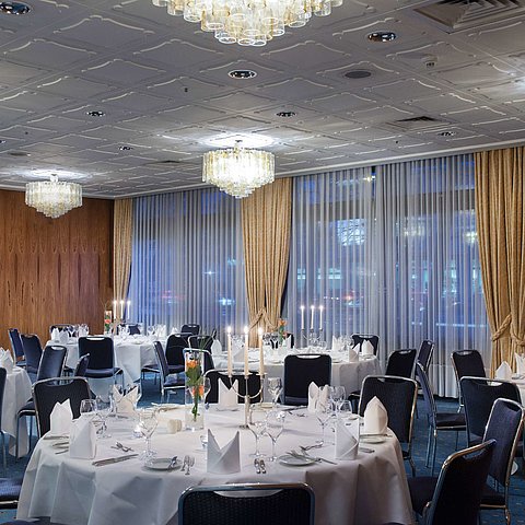 Elegantly set event room at Maritim Hotel Darmstadt with round tables, candles, and a sophisticated ambiance.