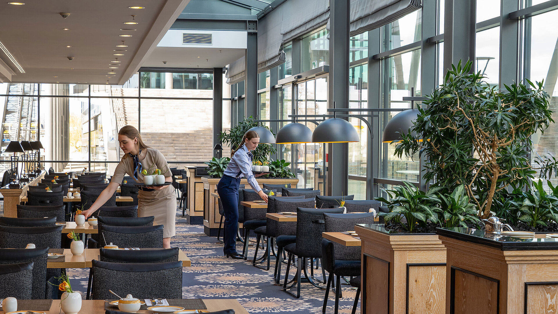 Bright interior of Restaurant Wintergarten at Maritim Hotel Dresden with large windows and elegantly set tables.