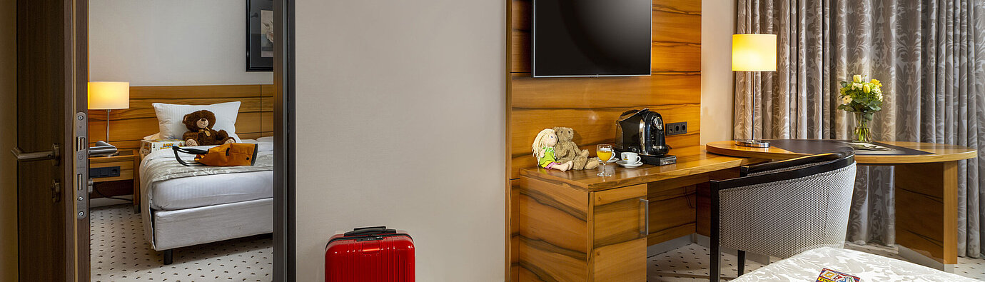 Comfort Family room Family room at Maritim Hotel Bad Homburg with separate kids' room, teddy bears, and red suitcase.