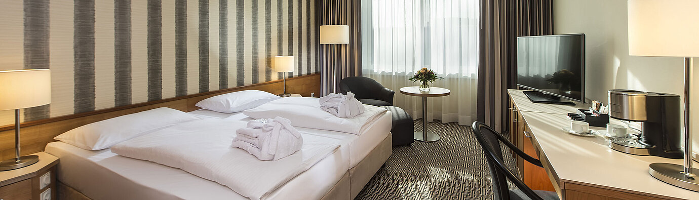 Bright double room with desk, armchairs and large bed at the Maritim Hotel Stuttgart