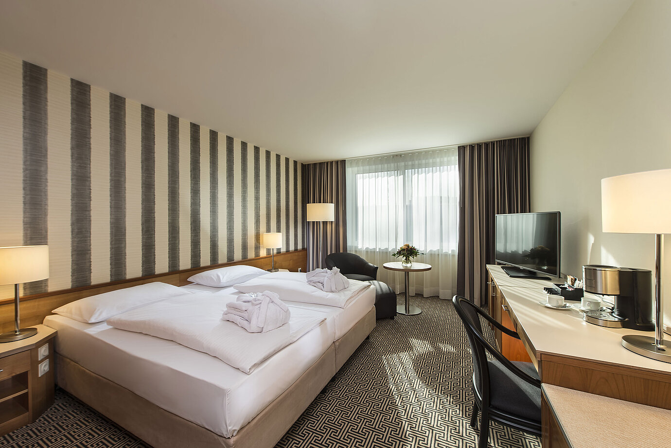 Bright double room with desk, armchairs and large bed at the Maritim Hotel Stuttgart