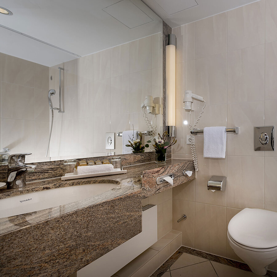 Modern bathroom at Maritim Seehotel Timmendorfer Strand with sink, mirror, shower, toilet, and bathtub.