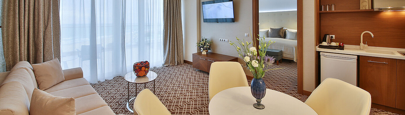 Modern suite with living area, kitchenette, balcony windows and separate bedroom